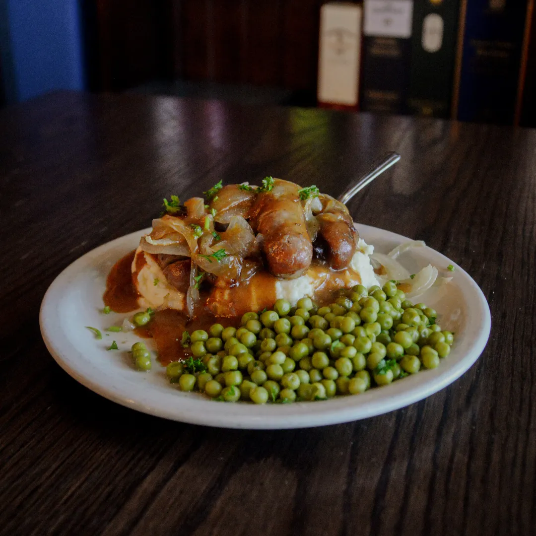 Brazen Head bangers and mash with caramelized onions, gravy, and peas